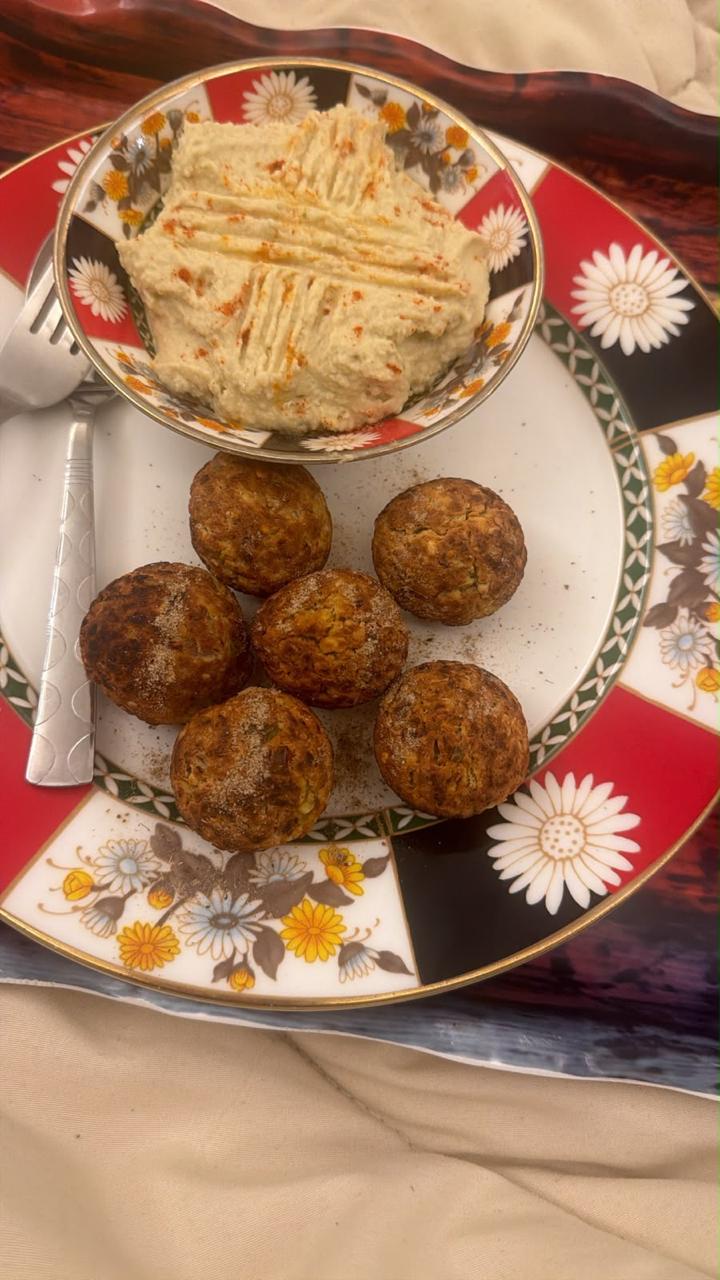 Six appe arranged on a floral plate with a small bowl of blended dip dusted with chilli powder